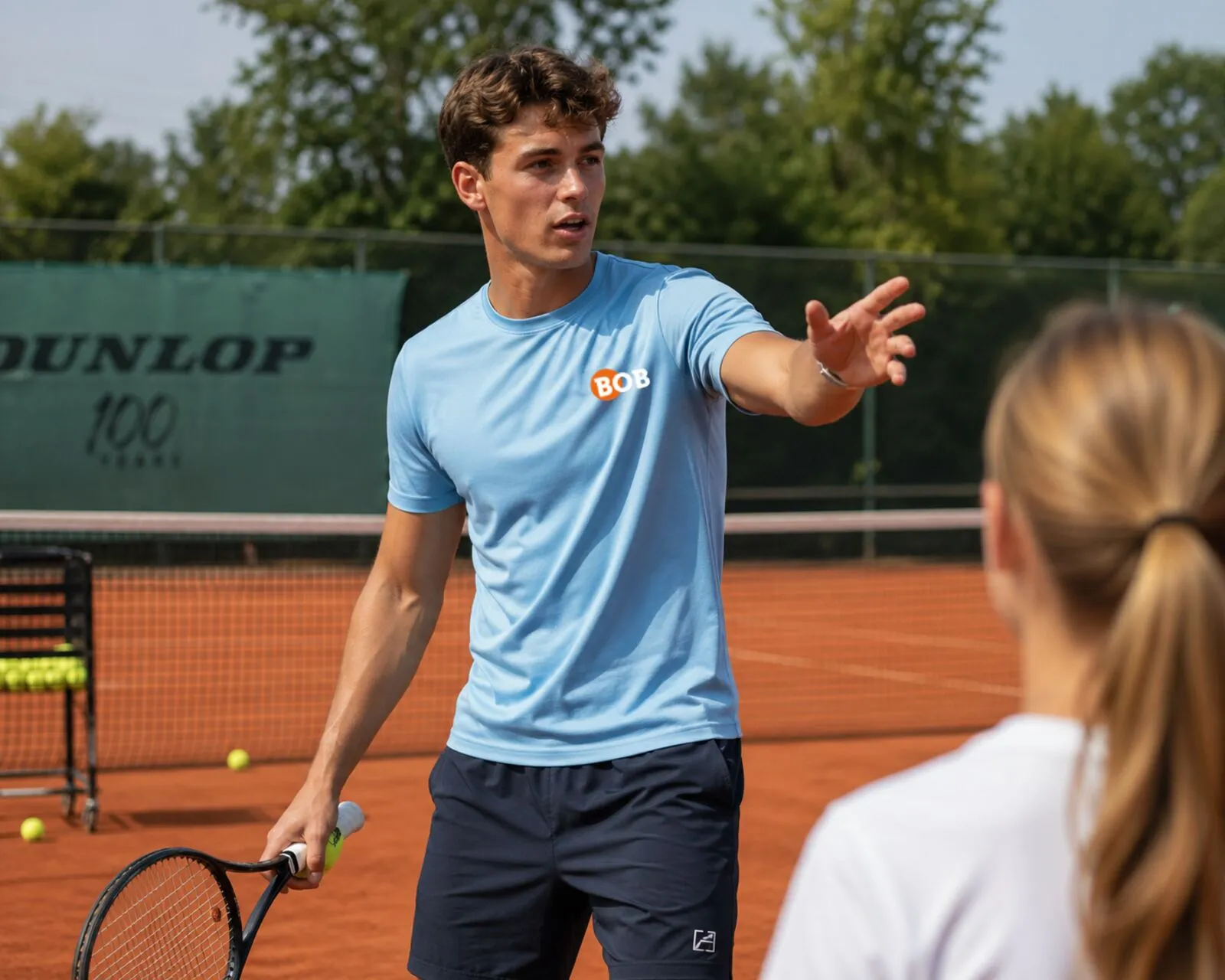 Spaanse BOB-trainer geeft tennisles aan een jonge speler op gravel